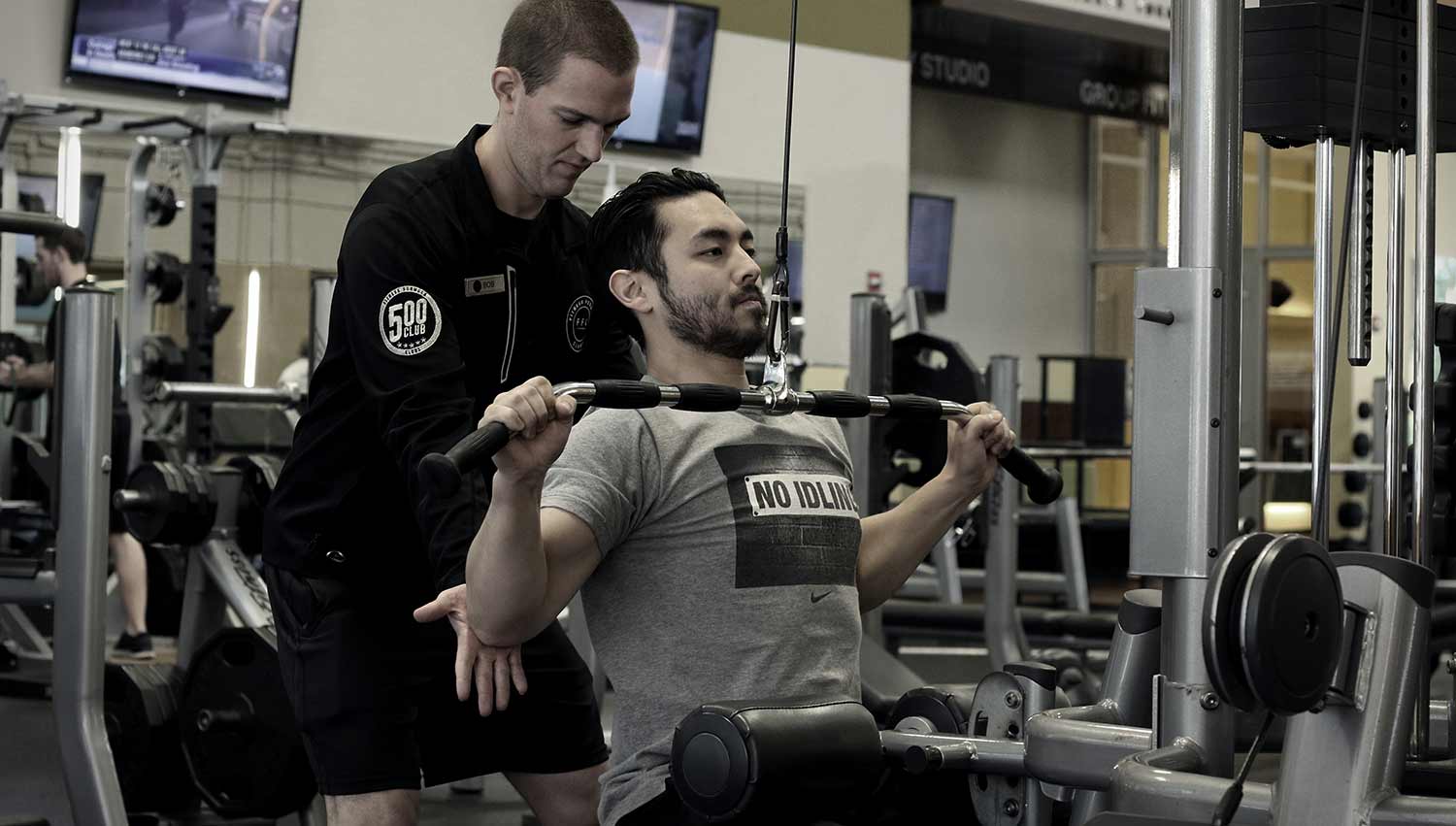 Personal trainer helping a member with their form.