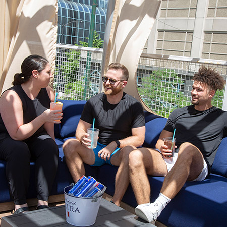 Three people enjoying a drink in a covered cabana