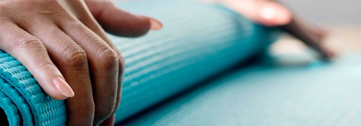 Woman rolling up a yoga mat.