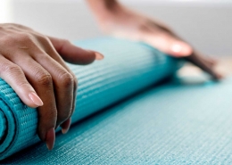 Woman rolling up a yoga mat.