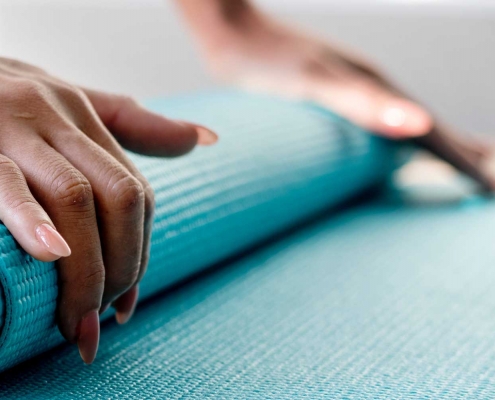 Woman rolling up a yoga mat.