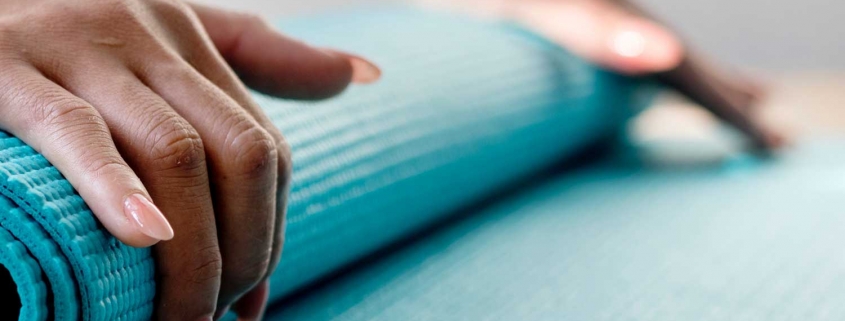 Woman rolling up a yoga mat.