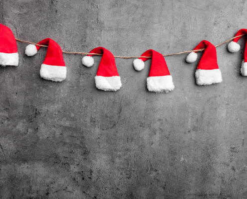 Santa hats on a string against gray wall