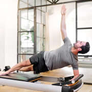 Man on Pilates reformer performing side plank