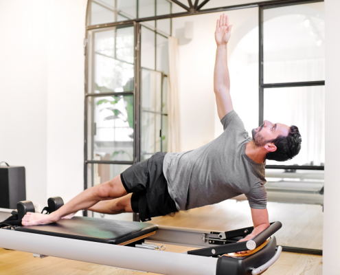 Man on Pilates reformer performing side plank