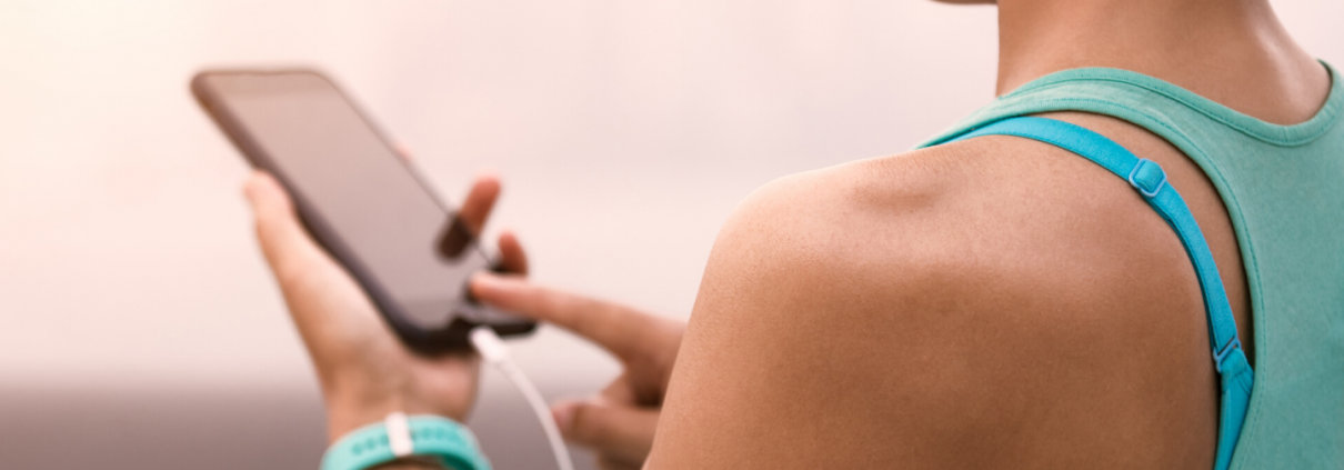 Female runner holding phone and listening to music with headphones on.