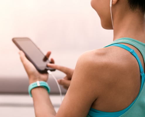 Female runner holding phone and listening to music with headphones on.