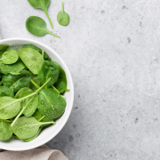 Image of a bowl of baby spinach on a granite countertop.