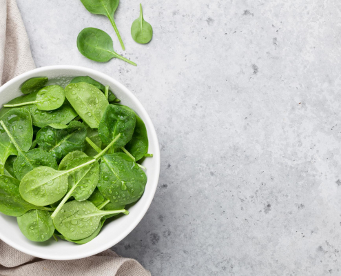 Image of a bowl of baby spinach on a granite countertop.