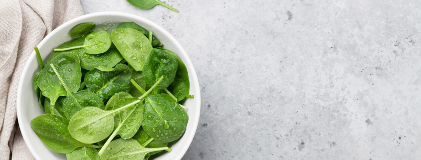 Image of a bowl of baby spinach on a granite countertop.