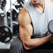 Fit strong man doing biceps curl in gym