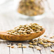 Uncooked dried lentil in wooden spoon.