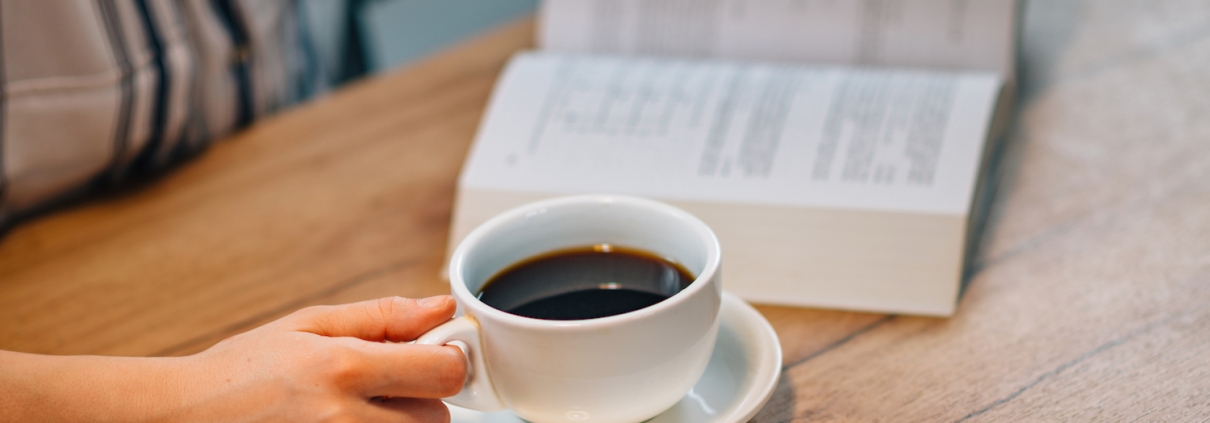 Woman drinking coffee and reading book