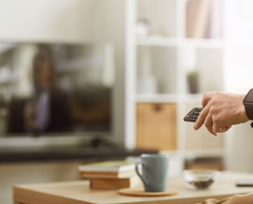 Person holding a remote and pointing it at a television