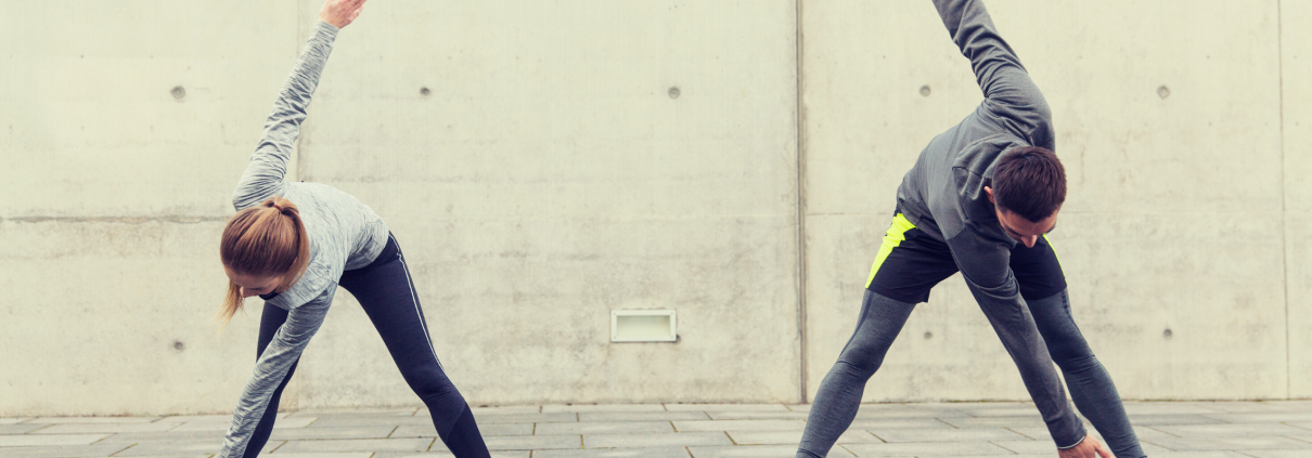 Man and woman outside in running gear stretching