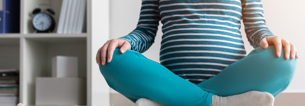 Pregnanct woman sitting cross legged on rug at home