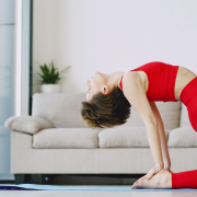 Woman in camel pose doing yoga on mat in home.