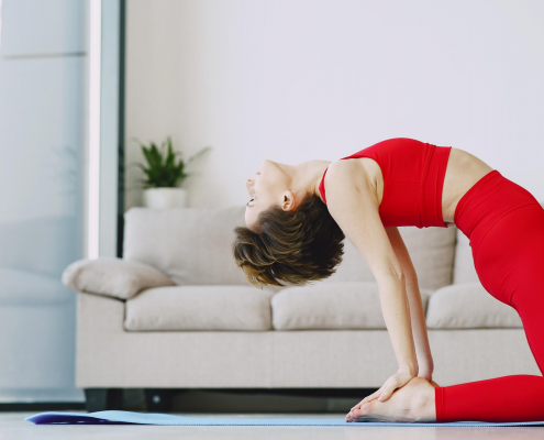 Woman in camel pose doing yoga on mat in home.