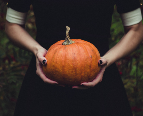 Girl wearing black dress holding a pumpkin
