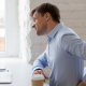 Man at desk holding his lower back