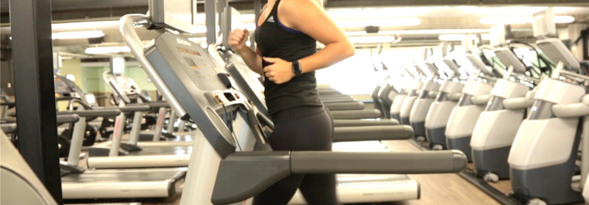 Woman running on treadmill wearing a mask