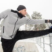 Man in his 30s stretching outside in the snow after a run