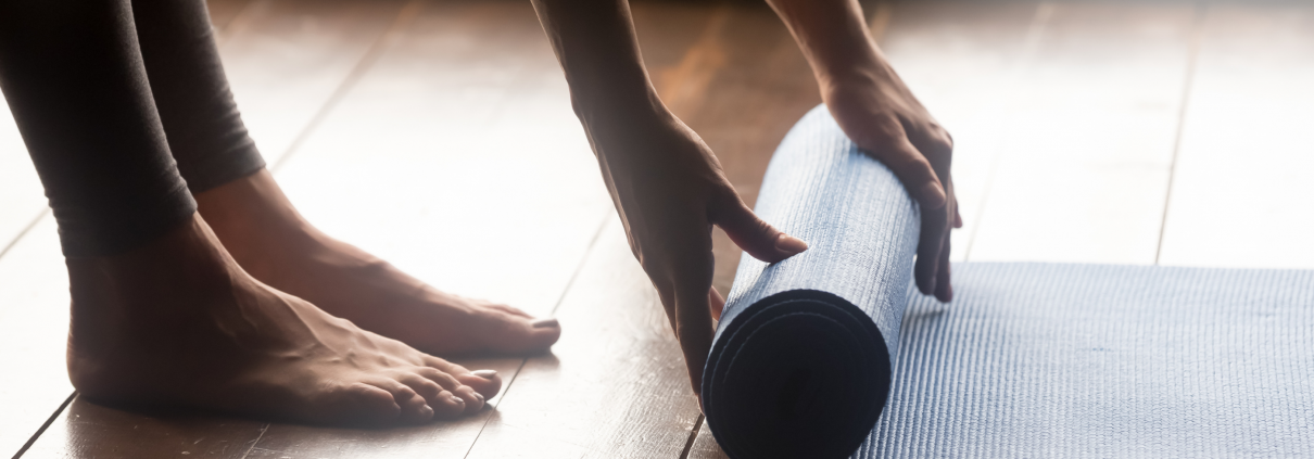 Woman unrolling yoga mat on floor