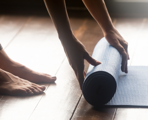 Woman unrolling yoga mat on floor