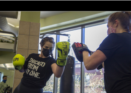 Two women boxing with gloves in a fitness club