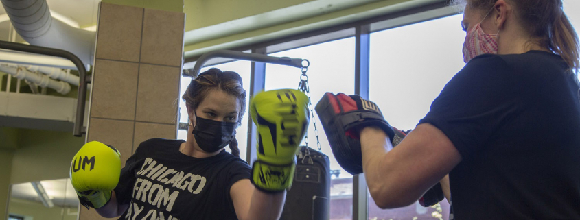 Two women boxing with gloves in a fitness club