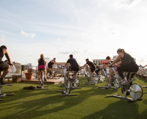 People on spin bikes taking a class on the FFC Gold Coast rooftop turf area.