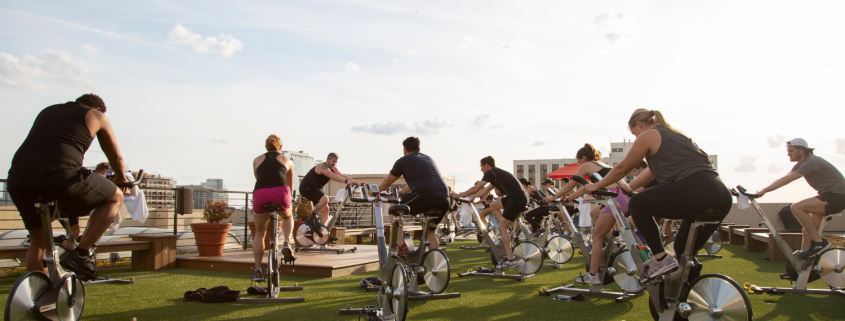 People on spin bikes taking a class on the FFC Gold Coast rooftop turf area.