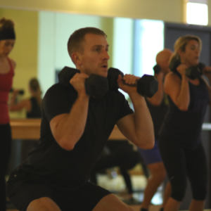 Man squatting with weights in a Low Body Meltdown group fitness class in Chicago