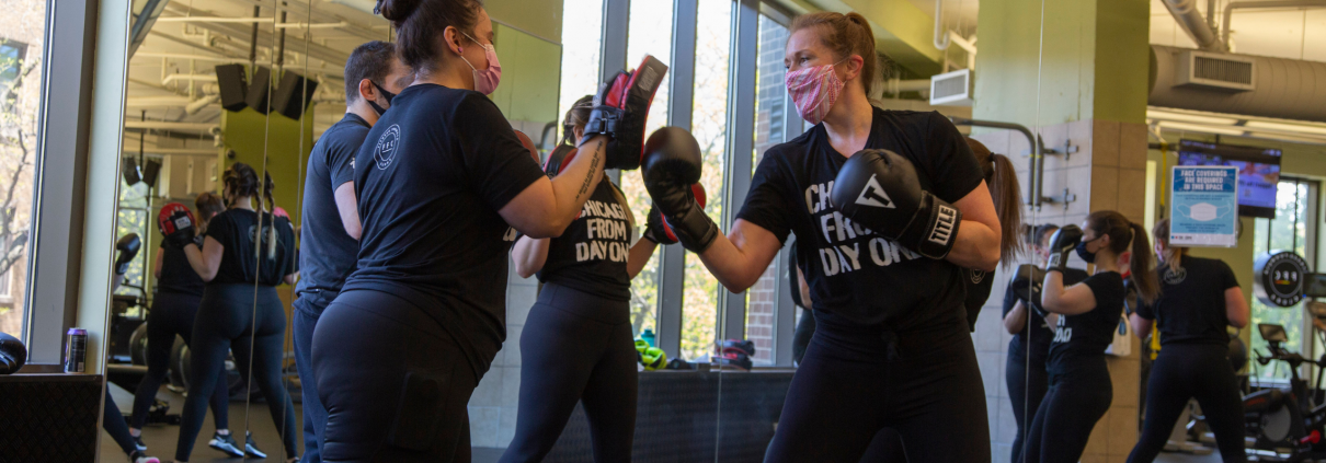 Two women participating in a small group boxing class at a gym