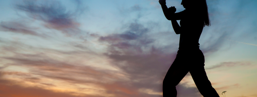 Outline of a woman at sunset with fists up in fighting stance