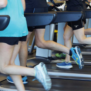 Three people running on treadmills at the gym