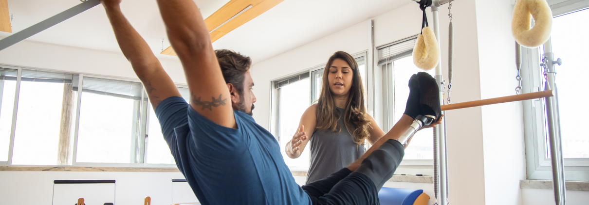 Woman instructing a man on the Pilates apparatus