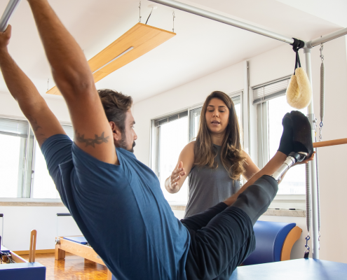 Woman instructing a man on the Pilates apparatus