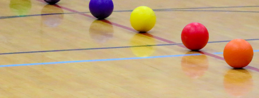 Dodgeballs lined up in a row on basketball court