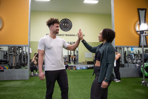 A man and woman high fiving in a gym