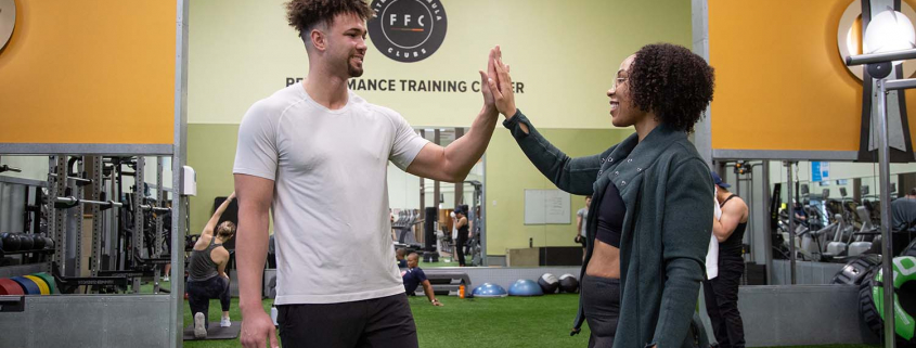 A man and woman high fiving in a gym
