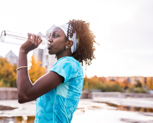 Woman drinking water out of a water bottle outside