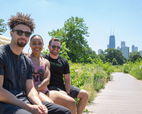 2 men and a woman sit on a bench outside in FFC gear in Lincoln Park