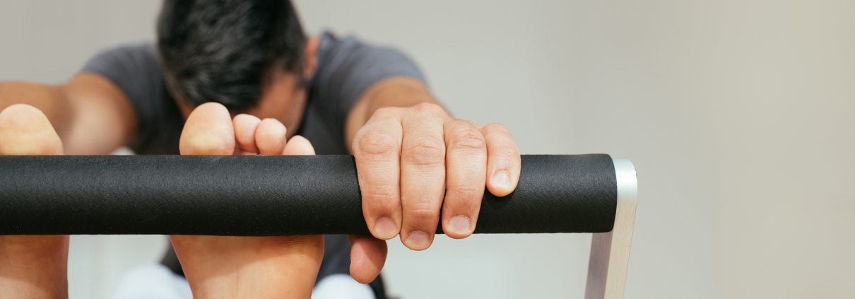 Man stretching his hamstrings on a Pilates reformer