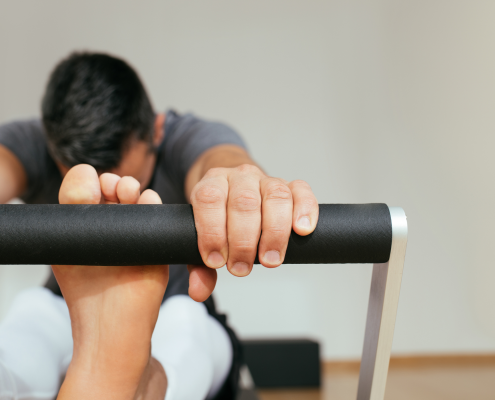 Man stretching his hamstrings on a Pilates reformer