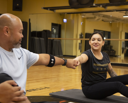 2 people bumping fists while sitting on exercise mats