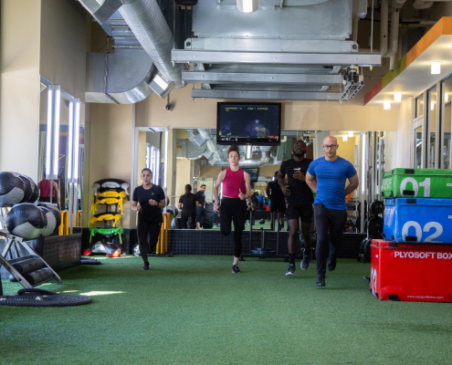 Image of 4 people running on indoor turf in a gym