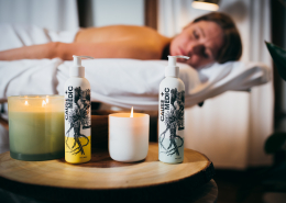 CBD Massage products displayed on a side table with a woman on a massage table in the background.