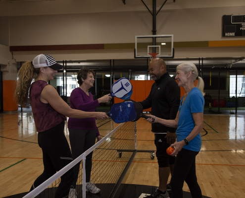 group of 4 people touching paddles after a pickleball game