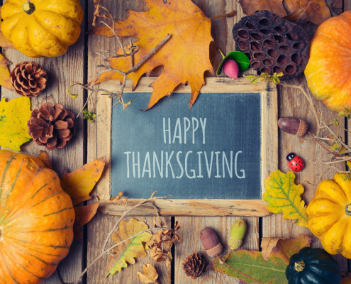 Thanksgiving background with chalkboard. Autumn pumpkin and fall leaves on wooden table. View from above